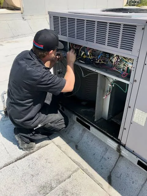 Technician working inside a rooftop HVAC unit